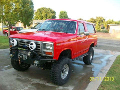 1985 Ford Bronco - This red Ford Bronco features off-road modifications including a winch and auxiliary lights.
