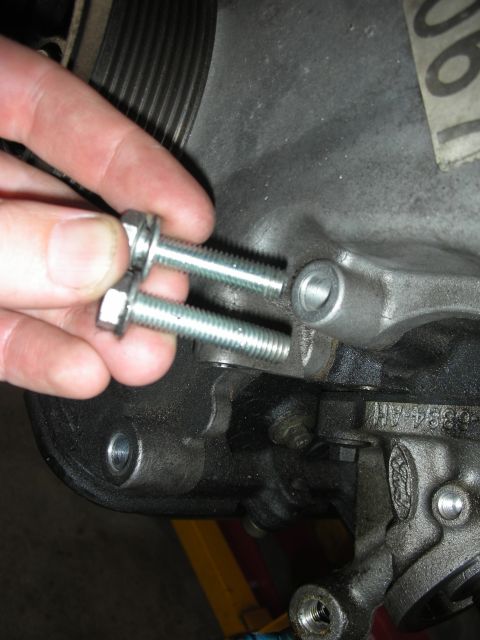 1992 Ford Crown Victoria - Bolts being held near an engine block, likely for an engine rebuild or repair.