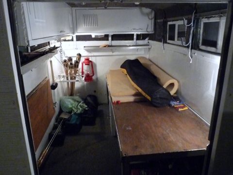 2006 Ford E350 - The interior of a cargo van is equipped with a sleeping area and storage for torches.