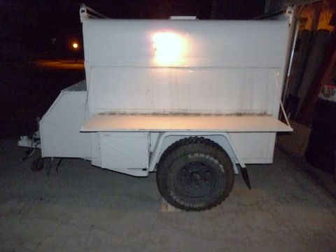 2006 Ford E350 - A white trailer is parked indoors, showing its side profile with a single large wheel and an open cargo bed.