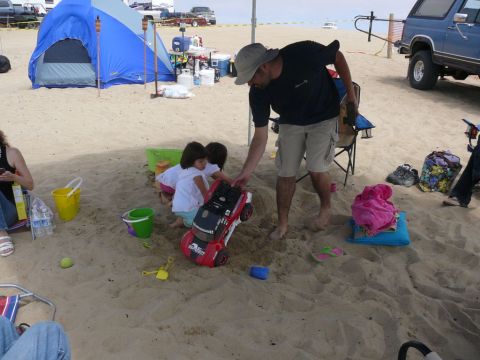 1988 Ford Bronco - A family enjoys a day at the beach with tents, chairs, and toys scattered on the sand.