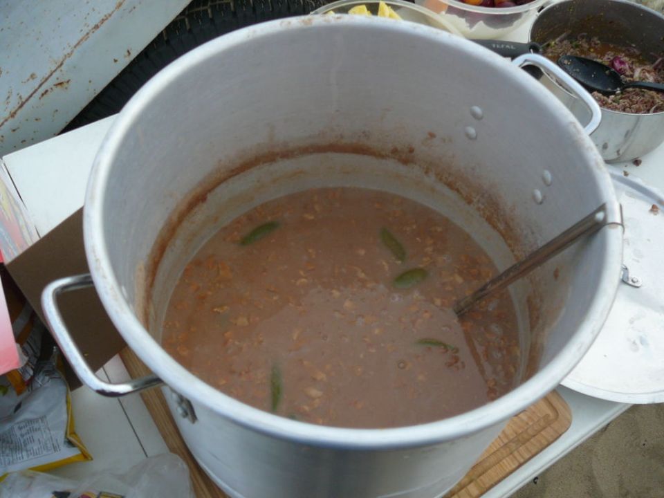 Big pot of stew with green peppers, next to another pot of food