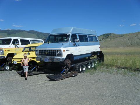 1981 Ford E350 - Van converted to tracks, parked with other vehicles in a rural setting.