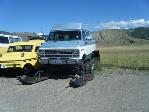 1981 Ford E350 - A van is outfitted with snow tracks for off-road travel, parked beside another unique vehicle.