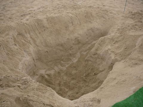 1988 Ford Bronco - A deep excavation in the sand reveals layered earth and a distant pole, with a website watermark at the bottom right.