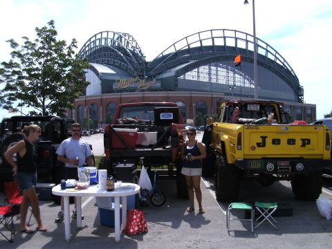 1994 Ford F-250 - Two lifted pickup trucks are parked in front of Miller Park stadium on a sunny day.