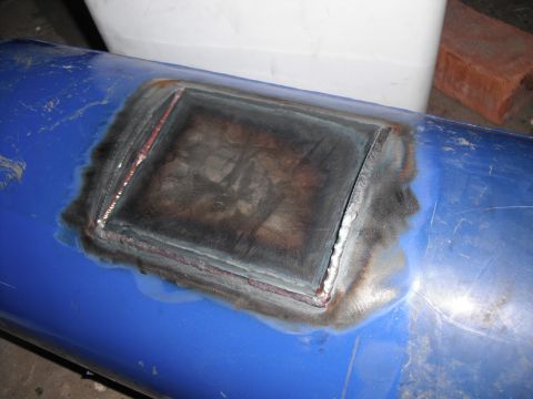 1991 Ford Bronco - A close-up view of a welded patch on a blue cylindrical object, showing signs of repair and discoloration.
