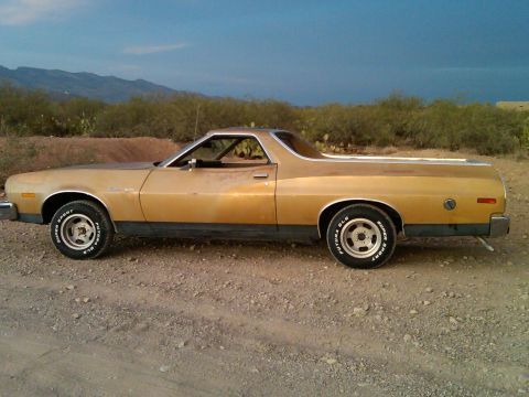 1973 Ford Ranchero - This Ford Ranchero is seen from the side, parked in a dry, outdoor environment under a partly cloudy sky.