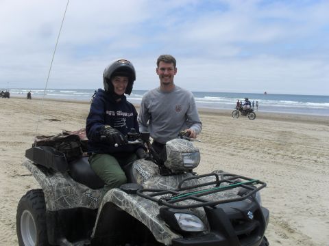 1991 Ford F-350 - Two people pose on an all-terrain vehicle on a beach with the ocean in the background.