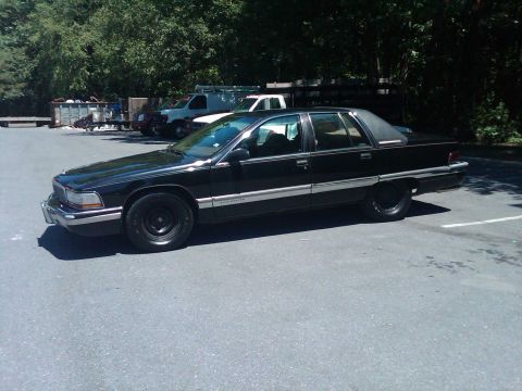 1991 Ford Crown Victoria LTD - This black sedan, identified as a Roadmaster, is parked in an outdoor lot with other vehicles present.