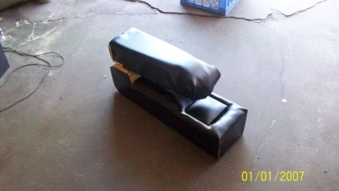 2004 Ford Crown Victoria - A black vinyl center console with a storage compartment sits on a concrete floor.