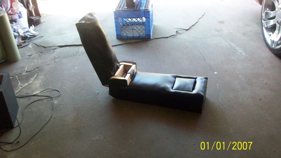 Car seat console with open storage compartment and cup holder, on concrete floor