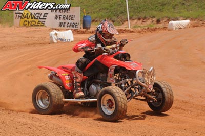 2004 Honda TRX 400 EX - A rider navigates a dirt track on a red 2004 Honda TRX 400 EX ATV.