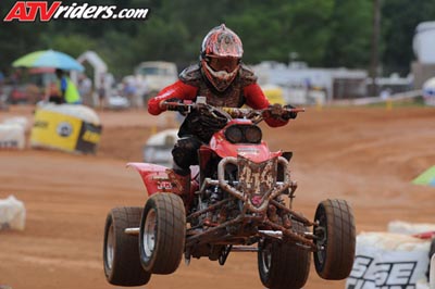 2004 Honda TRX 400 EX - A rider on a red ATV soars through the air during a race, with prominent watermarks from ATVriders.com and Supermotors.net on the image.