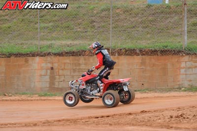 2004 Honda TRX 400 EX - A rider on a red ATV kicks up dust while navigating a dirt track.
