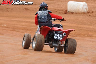 2004 Honda TRX 400 EX - A rider on a red ATV with the number 414 navigates a dirt track, viewed from the rear.