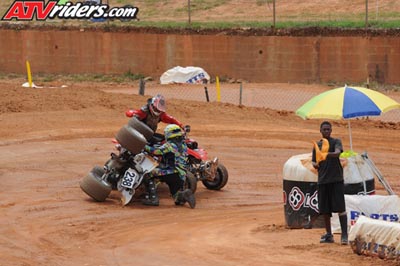 2004 Honda TRX 400 EX - ATV riders compete on a dirt track, with one ATV overturned and its rider on the ground.