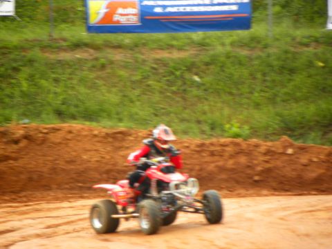 2004 Honda TRX 400 EX - Rider on a red ATV navigates a dirt track with a banner in the background.