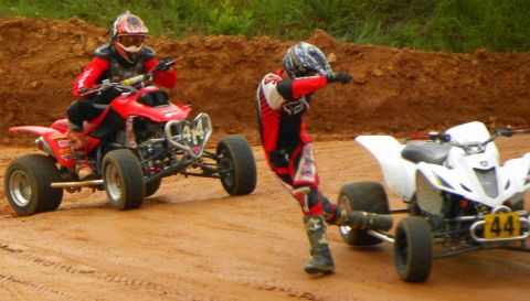 2004 Honda TRX 400 EX - Two ATVs and riders on a dirt track during a race or practice session.