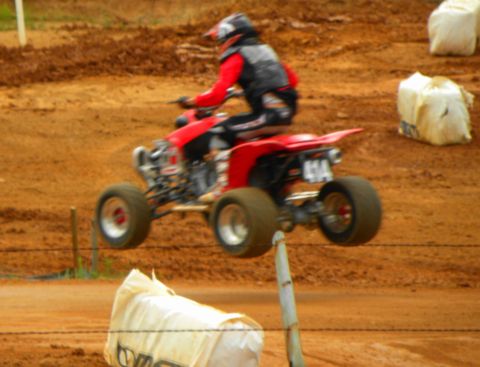 2004 Honda TRX 400 EX - Rider on a red ATV performs a jump on a dirt track, with the number 414 displayed.