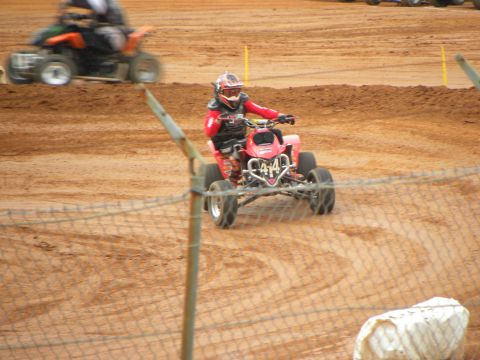 2004 Honda TRX 400 EX - A rider on a red ATV navigates a dirt track during a race.