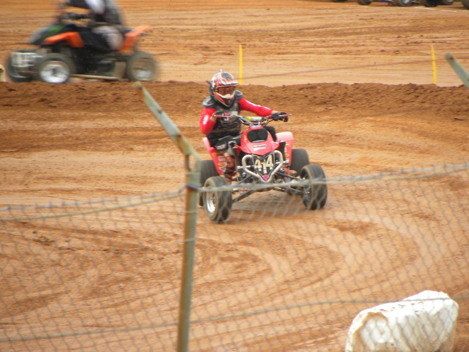 Red ATV with number 414 on front, rider in red gear, on dirt track