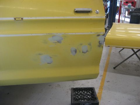 1978 Ford Bronco - A yellow vehicle door and fender show areas of primer, indicating repair work is in progress.