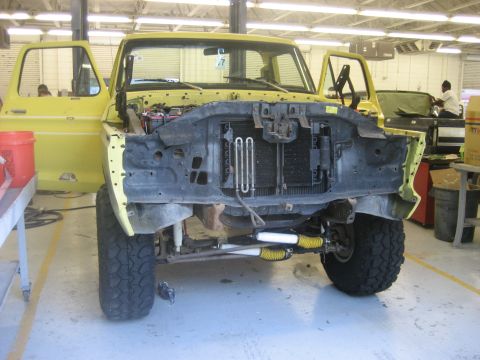 1978 Ford Bronco - Front view of a yellow 1978 Ford Bronco undergoing repairs in a workshop.