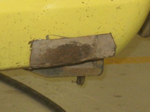 1978 Ford Bronco - Close-up of a yellow vehicle's lower body panel showing a patch of rust repair.