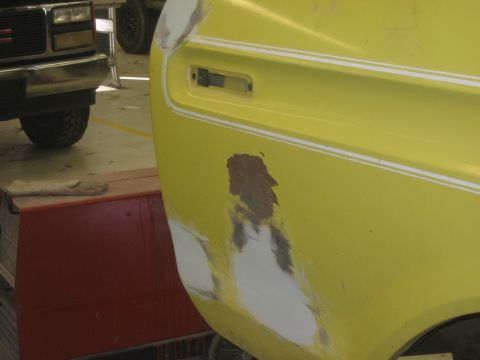 1978 Ford Bronco - A yellow vehicle's fender is shown with visible body filler and primer, indicating repair work is in progress.