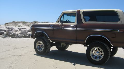 1979 Ford Bronco - This lifted 1979 Ford Bronco is parked on a sandy beach under a clear blue sky.