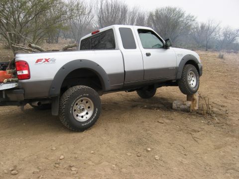 1979 Ford Bronco - A silver and grey pickup truck with FX4 badging is shown in a side view, demonstrating its off-road capabilities.