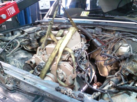 1990 Ford Bronco - Engine removal in progress, with a crane lifting the unit out of the vehicle's engine bay.