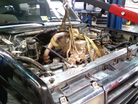 1990 Ford Bronco - Engine removal in progress with a crane, showing the vehicle's engine bay.