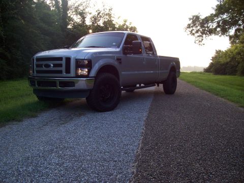 2008 Ford F-250 - A silver Ford F-250 Super Duty pickup truck is parked on a gravel road with trees in the background.