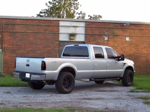 2008 Ford F-250 - This silver Ford F-250 Super Duty pickup truck is parked on a gravel lot in front of a brick building.