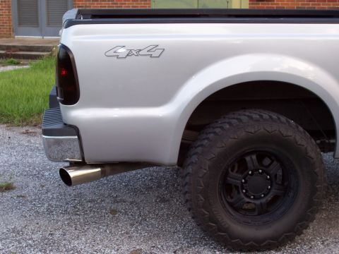 2008 Ford F-250 - A silver pickup truck's rear side is shown, a 4x4 badge and a large, tire.