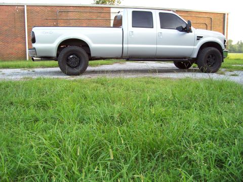 2008 Ford F-250 - A silver 2008 Ford F-250 crew cab pickup truck is parked on a gravel surface with grass in the foreground.