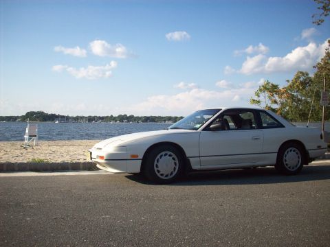1992 Nissan 240SX - A white 1992 Nissan 240SX coupe is parked by the water on a sunny day.