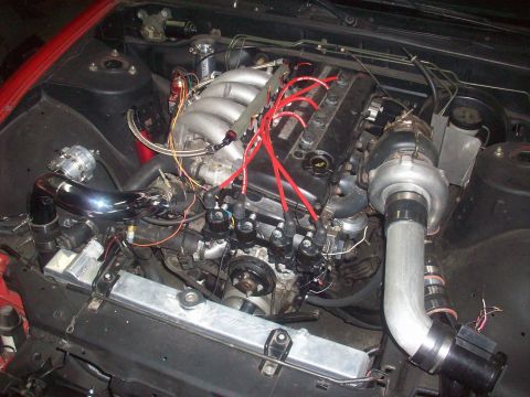 1992 Nissan 240SX - Engine bay view of a turbocharged inline-six engine with custom intercooler piping and a blow-off valve.