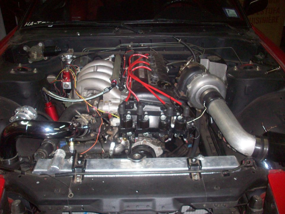Engine bay with a large turbocharger, intake piping, and aftermarket radiator