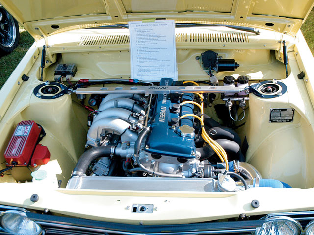 Yellow engine bay with a blue Nissan Twin Cam engine, silver intake manifold, and red MSD ignition box