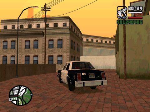2000 Mercury Grand Marquis - A black and white police car is seen from the rear, parked on a brick-paved street in front of a building.