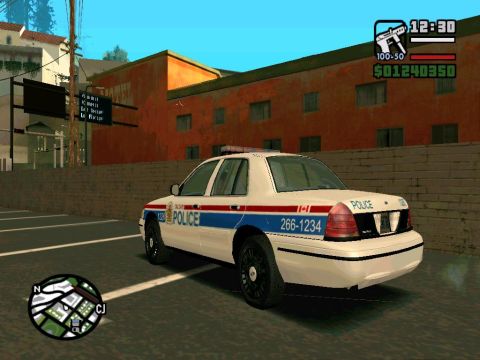 2000 Mercury Grand Marquis - A white police car with 'POLICE' text and red and blue stripes is seen from the rear in a parking lot.