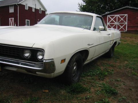 1971 Ford Ranchero - White Ford Ranchero pickup truck parked in a grassy area near a red barn.