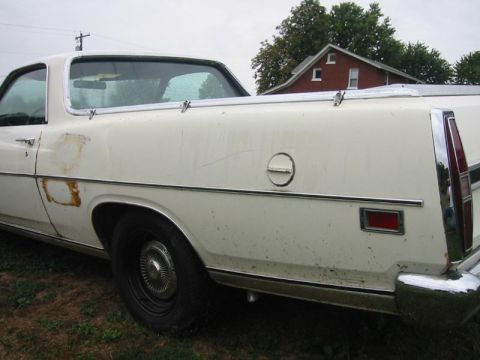 1971 Ford Ranchero - Rear view of a white 1971 Ford Ranchero pickup, showing chrome accents and visible rust damage on the body.