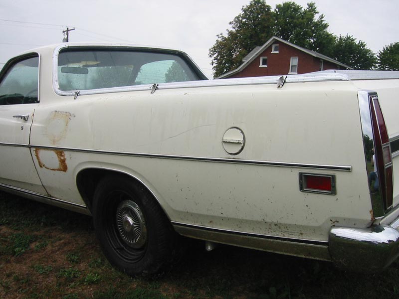White 1971 Ford Ranchero rear quarter panel with chrome trim and rust spots