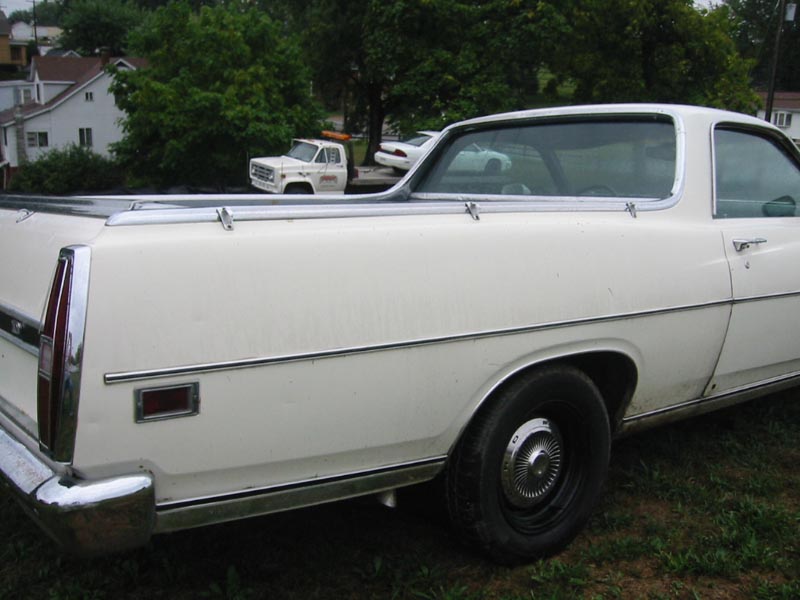 White pickup truck parked in front of a white car, side view