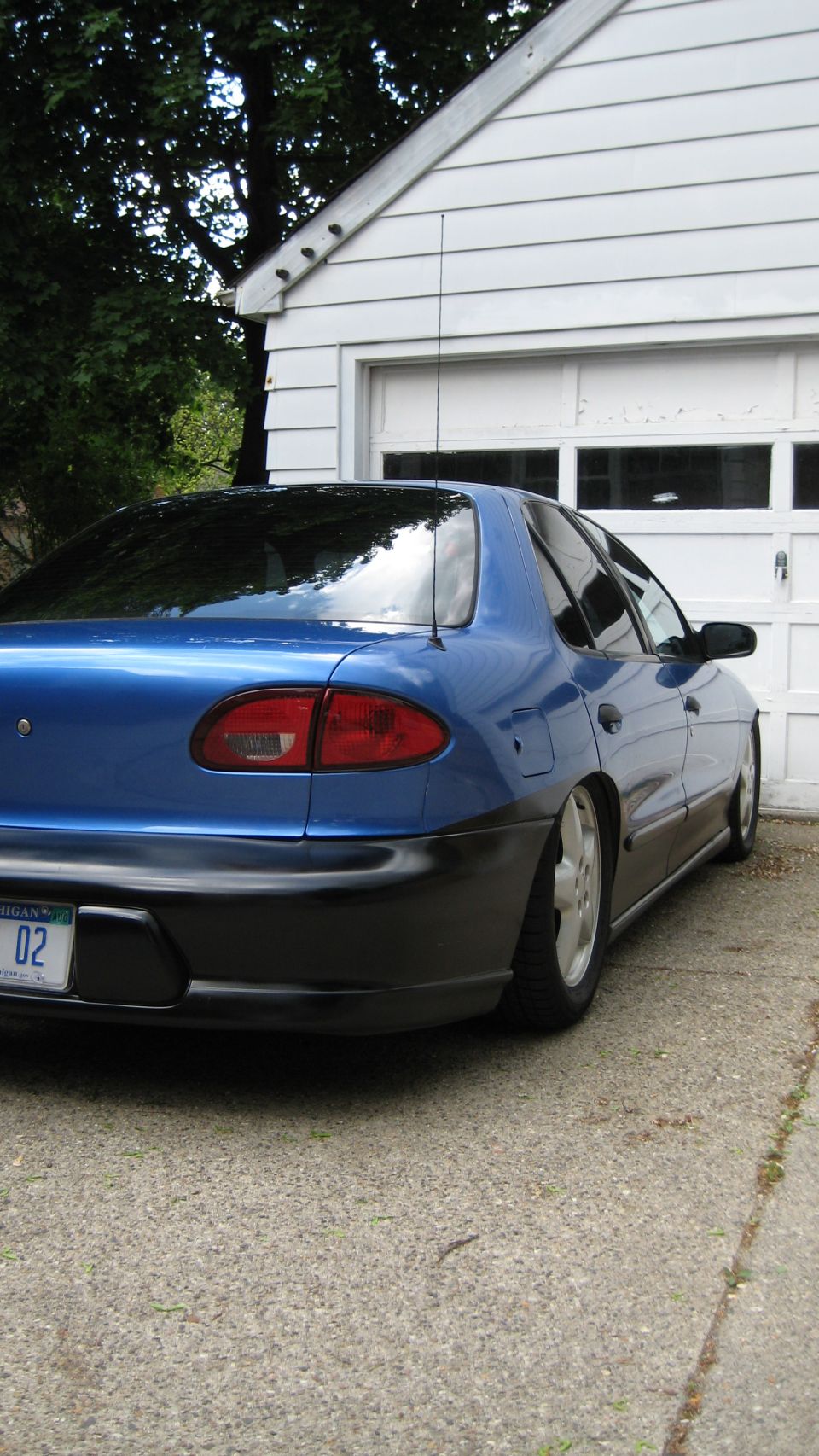 blue sedan parked in front of a garage, lowered suspension