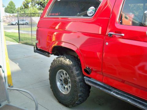 1985 Ford Bronco - This red SUV features a side exhaust pipe and large off-road tires, suggesting it is modified for off-road use.